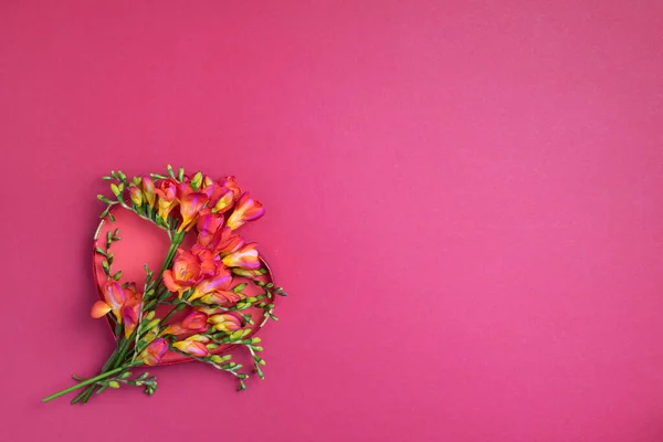 Voorjaar freesia bloemen over rood hart op roze achtergrond. Bovenaanzicht. Plat gelegd. Zomer en lente concept. Valentijnsdag, vrouwendag concept. Lente of zomer banner met kopieerruimte — Stockfoto