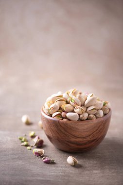 Ahşap desenli arka planda ahşap kasede yeşil şam fıstığı. Uzayı kopyala Süper yemek, vejetaryen, vejetaryen gıda konsepti. Şam fıstığı desenli, seçici odaklanma. Sağlıklı çerez.