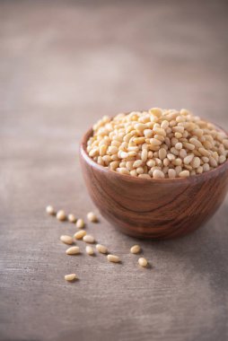 Ahşap desenli arka planda ahşap kasede çiğ çam fıstığı. Uzayı kopyala Süper yemek, vejetaryen, vejetaryen gıda konsepti. Sedir çam fıstığı deseni, seçici odaklanma. Sağlıklı çerez.