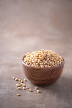 Ahşap desenli arka planda ahşap kasede çiğ çam fıstığı. Uzayı kopyala Süper yemek, vejetaryen, vejetaryen gıda konsepti. Sedir çam fıstığı deseni, seçici odaklanma. Sağlıklı çerez.