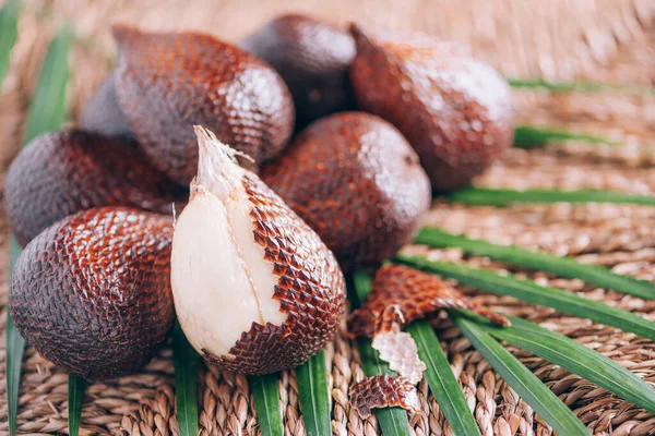 Vörös Salacca. Salak, kígyó gyümölcsök pálmalevéllel, rattan háttérrel. Másold a helyet. Salacca zalacca vagyok. Salak pálma gyümölcsök közelsége. Trópusi utazás, egzotikus gyümölcs. Vegán és vegetáriánus fogalom — Stock Fotó