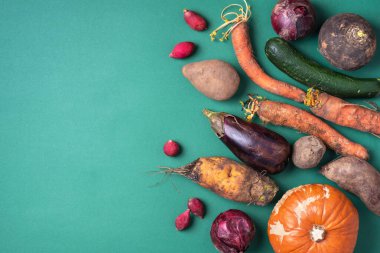 Son moda çirkin organik sebzeler. Yeşil arka planda taze patlıcan, soğan, havuç ve kabak çeşitleri. Üst Manzara. Çirkin yemekler pişirmek. Gmo olmayan sebzeler