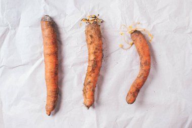 Kağıt üzerinde çirkin şekilsiz havuçlar. Sıfır atık üretimi kavramı. Üst Manzara. Uzayı kopyala Gmo olmayan sebzeler