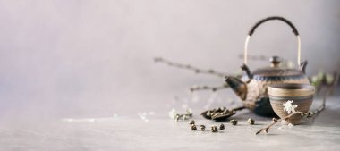 Siyah ve kahverengi çaydanlık ve çay fincanları, çiçek açan çiçekler gri arka planda kiraz dalları. Üst Manzara. Uzayı kopyala Geleneksel Asya çay töreni konsepti