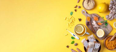 Tıbbi bakım konsepti. Soğuk algınlığı, grip. Zencefil, limon, bal, haplar, ilaçlar, takviyeler, sarı arka planda termometre. Doğal alternatif bütünsel yaklaşım. Üst görünüm, alanı kopyala