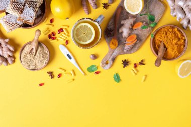 Tıbbi bakım konsepti. Soğuk algınlığı, grip. Zencefil, limon, bal, haplar, ilaçlar, takviyeler, sarı arka planda termometre. Doğal alternatif bütünsel yaklaşım. Üst görünüm, alanı kopyala