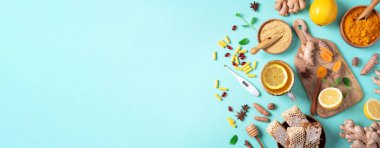 Sağlık, grip ve soğuk algınlığı tedavisi. Naturopati konsepti. Zencefil, limon, bal, haplar, ilaçlar, takviyeler, mavi arka planda termometre. Doğal alternatif bütünsel yaklaşım. Üst görünüm, alanı kopyala