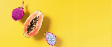 Yarım papaya, pitahaya, sarı arka planda ejderha meyvesi. Üst Manzara. Uzayı kopyala Yaz zamanı. Tropik seyahat, egzotik meyve. Vejetaryen ve vejetaryen kavramı