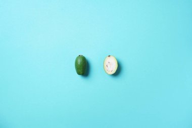 Mavi arka planda tropik meyve feijoa 'sı. Üst Manzara. Uzayı kopyala Acca sellowiana. Yaratıcı tasarım afişi. Yaz zamanı. Tropik seyahat, egzotik meyve. Vejetaryen ve vejetaryen kavramı