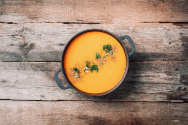 Balkabağı çorbası ahşap arka planda demir tencerede. Üst Manzara. Uzayı kopyala Organik vejetaryen malzemeler ve mutfak aletleri. Sağlıklı, temiz yemek ve yeme konsepti. Vejetaryen diyeti. Sıfır atık