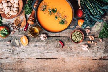 Organik vejetaryen malzemeler ve mutfak aletleri. Sağlıklı, temiz yemek ve yeme konsepti. Vejetaryen diyeti. Sıfır kayıp. Üst Manzara. Uzayı kopyala Balkabağı çorbası ahşap arka planda demir tencerede.