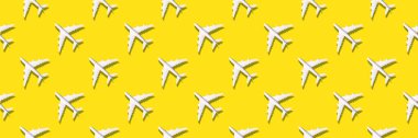 Sarı arka planda beyaz uçakların yaratıcı bayrağı. Seyahat, tatil konsepti. Seyahat, tatil yasağı. Uçuşlar iptal edildi ve tekrar devam edildi. Üst Manzara. Düz yatıyordu. Asgari tarz tasarım. Yaz deseni