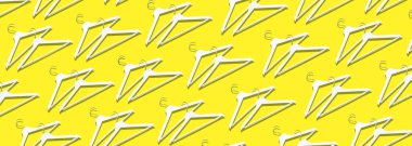 Beyaz elbise askılarının üst görüntüsü sarı arkaplanda, fotokopi alanı da var. Düz yatıyordu. Minimalizm tarzı ve azalma. Yaratıcı düzen. Moda, mağaza satışı, alışveriş konsepti. Kadınsı blog için afiş.