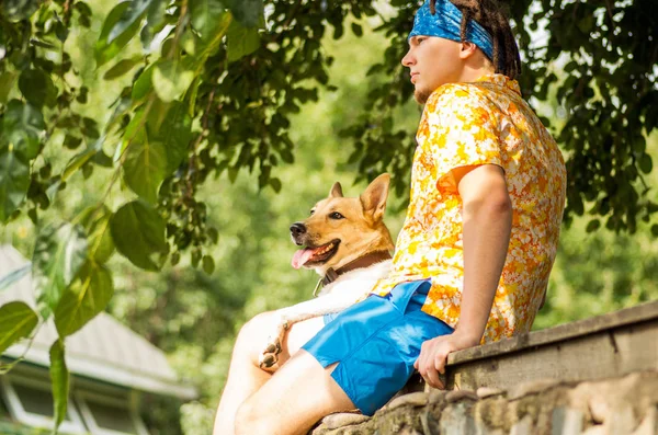 Ein Mann mit Hund sitzt auf den Steinen und schaut weit weg — Stockfoto