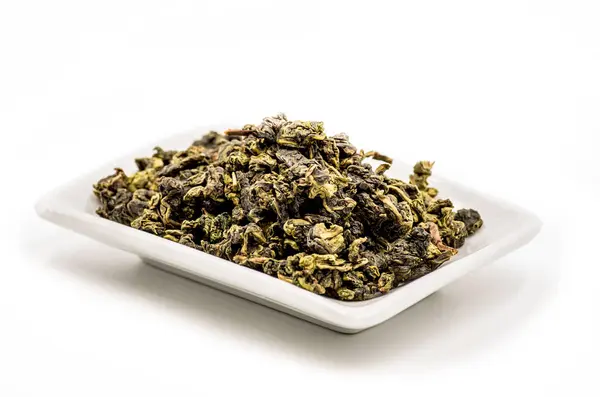 Te гуань инь зеленый чай листья на белой прямоугольной пластине — стоковое фото
