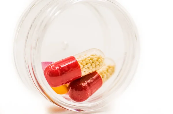 Píldoras de medicina coloridas en una caja de plástico redonda — Foto de Stock
