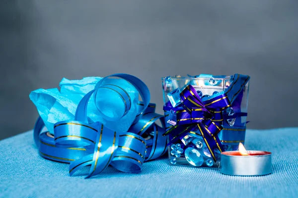 Vánoční řemesla složení na modrý ubrus. svíčka s drahokamy a modrá stuha — Stock fotografie