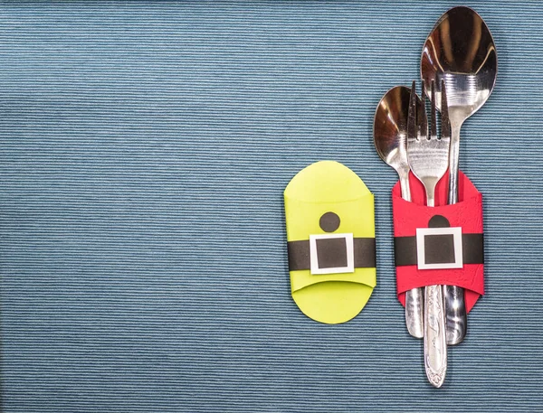 Noel çatal bıçak takımı sahipleri. Mavi masa örtüsü üzerinde kağıt el sanatları