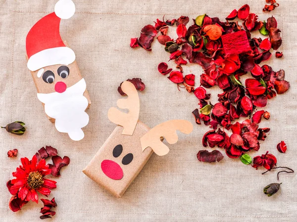 Vintage karácsonyi kézműves ajándék dobozok a lenvászon terítő piros aroma virágok és gyógynövények — Stock Fotó