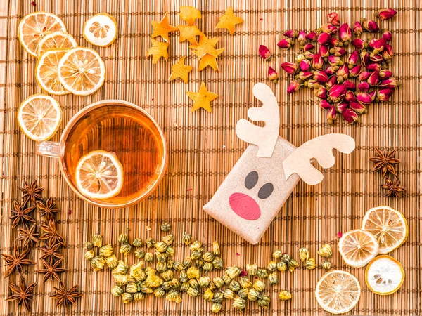 Ecological deer and santa crafts from recycled paper on linen background with cup of hot tea, lemons, oranges and decorations — Stock Photo, Image