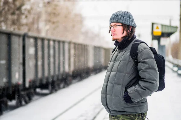 Homem está esperando por um trem na estação ferroviária ao ar livre na neve no inverno — Fotografia de Stock
