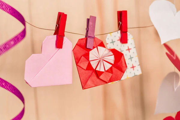 Valentine's day concept. origami paper hearts and envelopes with clips on wooden background — Stock Photo, Image