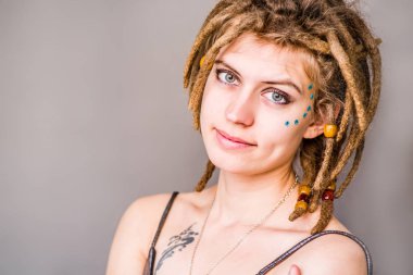 dreadlocks gri bir arka plan üzerinde gülümseyen gri elbiseli çekici kadın