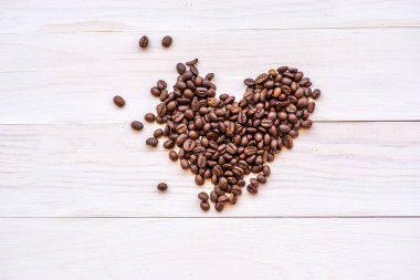 kahve çekirdekleri kalp dağılım beyaz rustik arka planda. Üstten Görünüm