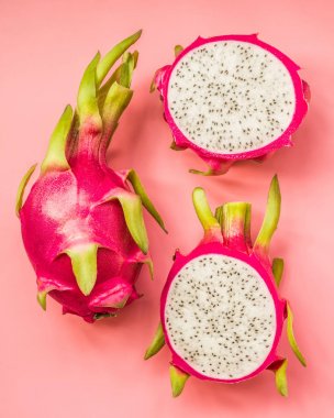 Üstten Görünüm tüm ve kesme dragonfruit pembe bir arka plan üzerinde