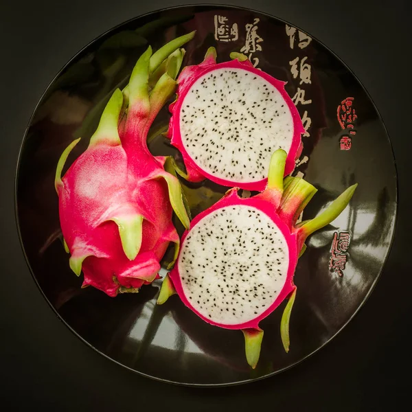 Dragon fruit on a black plate isolated on back background top view