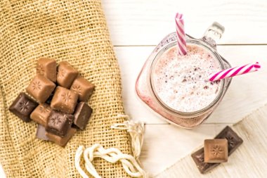 Berry ve meyve milkshake üstten görünüm çikolata ve kahve çanta eseriyle dekore Beyaz ahşap zemin üzerinde. yaz içecekler ve tatlılar. taze doğal organik milkshake içme payet düz iki ile yatıyordu