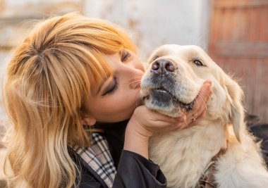 Sarışın kadın av köpeğini öpüyor.