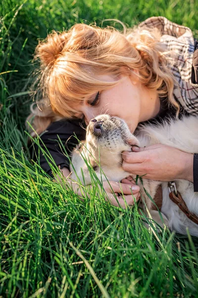 Hermosa mujer caucásica tendida en la hierba con su perro labrador retriever dorado en un parque al atardecer — Foto de Stock