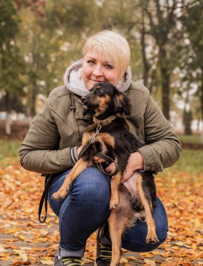 Parkta köpeğini kucaklayan bir kadın.