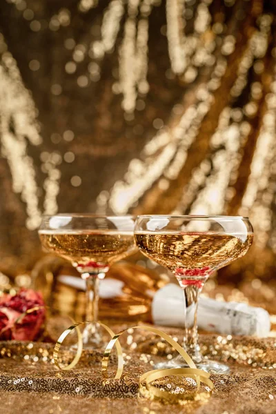 Dos flauta de champán con botella brillante sobre fondo dorado brillante —  Fotos de Stock