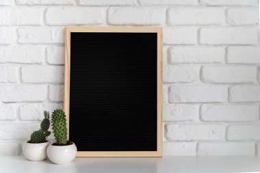black mock up felt letter board with small succulents on white brick background clipart