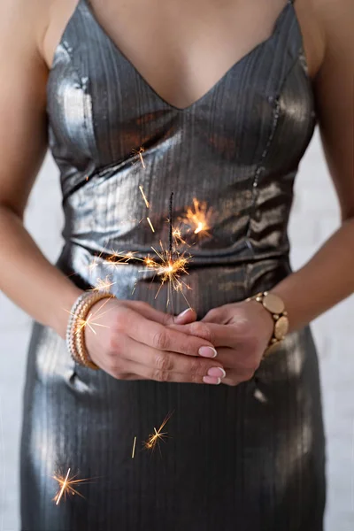 Woman in a party dress holding a sparkler in her hands — Stockfoto