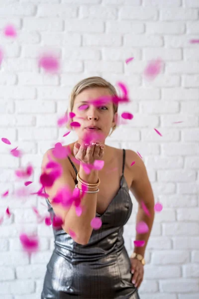 Caucásico mujer soplando colorido confeti en el aire — Foto de Stock