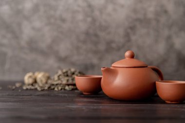 Koyu ahşap arka planda baharatlı Çin çayı seti ve kuru çay yaprakları.