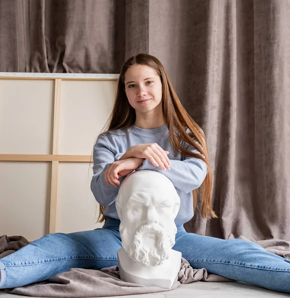 Giovane artista femminile seduta nel suo studio con la testa di tela e gesso Socrate — Foto Stock