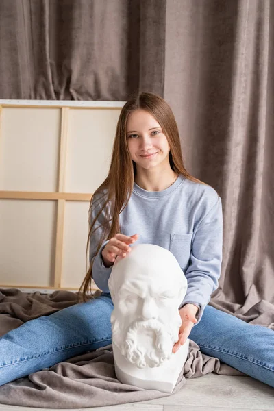 Young female artist sitting in her studio with the canvas and gypsum Socrates head — Stock Photo, Image