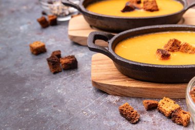 Demir kaplarda kızarmış ekmek ve balkabağı çorbası. Koyu arkaplanda kızarmış ekmek ve fotokopi alanı var.
