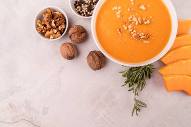 Kabak dilimleri ve baharatlarla süslenmiş kabak çorbası beyaz mermer arka planda fotokopi alanı ile süslenmiş.