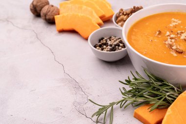 Kabak dilimleri ve baharatlarla süslenmiş kabak çorbası beyaz mermer arka planda fotokopi alanı ile süslenmiş.