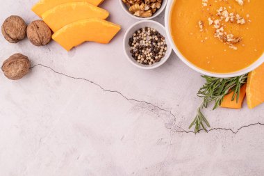 Kabak dilimleri ve baharatlarla süslenmiş kabak çorbası beyaz mermer arka planda fotokopi alanı ile süslenmiş.