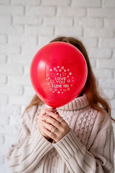 Mujer con globo rojo con las palabras I Love You sobre fondo de pared de ladrillo blanco — Foto de Stock