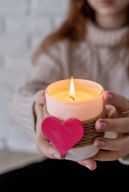 Kalp şeklinde bir mum tutan hoş bir genç kadın.