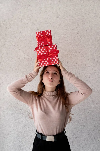 Молодая забавная женщина с кучей подарочных коробок на голове — стоковое фото
