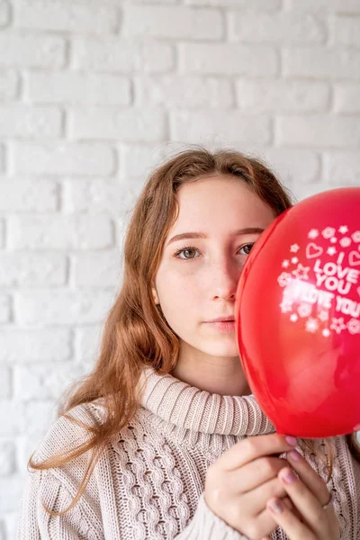 Joven mujer escondiendo su cara detrás del globo rojo con las palabras I Love You — Foto de Stock