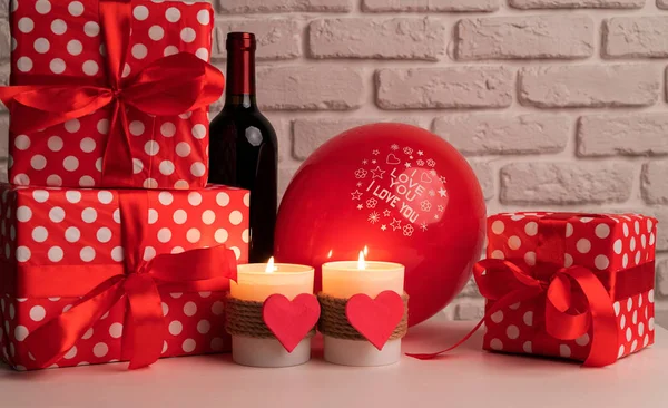День святого Валентина натюрморт с бутылкой вина, подарками, воздушными шарами и свечами в форме сердца — стоковое фото